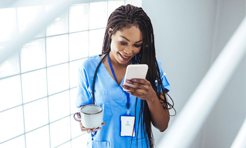 Young nurse in scrubs viewing mobile device.